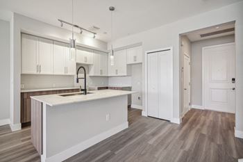 An open kitchen and living room with white cabinets and a white counter top